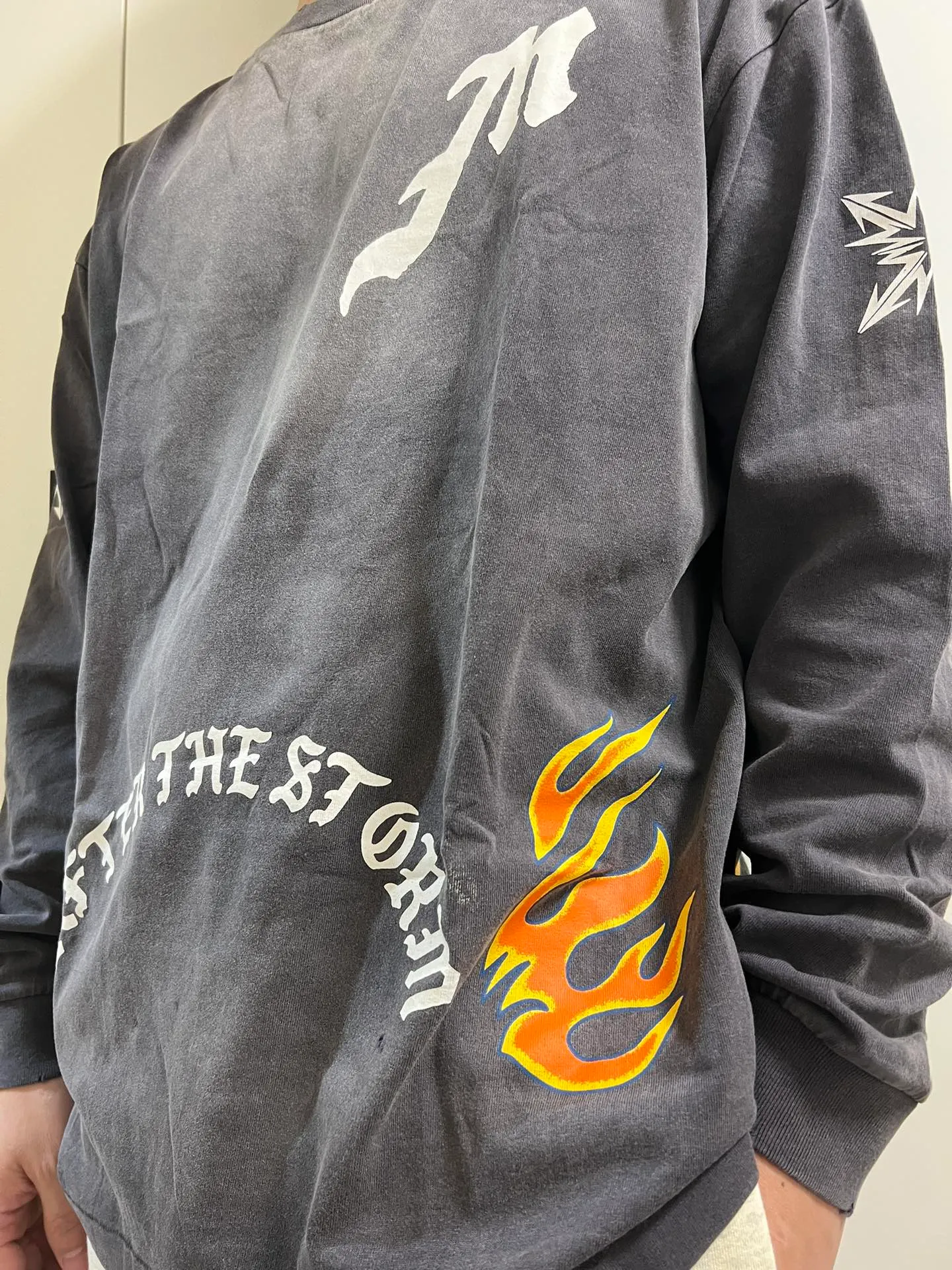 SAINT Mxxxxxx M/AFTER LS_TEE/BLACK Flame arrow Letter M retro distressed long tee Washed black S-XL Tubular fabric Assute ready-made garments dyed The whole piece is sprayed with horse-hair spray and then sprayed again to fade the color. The collar and cuffs are frayed. Many places are frayed. Extra large printing position. Very difficult to print. Complete accessories. With little angel anti-counterfeiting label.